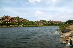 The sight of Hampi with massive boulders, ancient temples, and the Tungabhadra River flowing gently in the background
